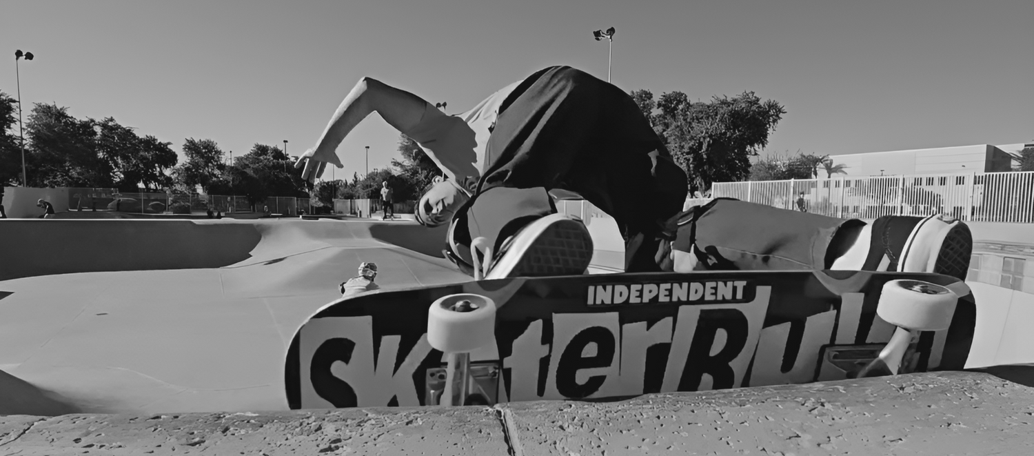 Skaterbuilt deck with Independent trucks rises over bowl coping at an outdoor skatepark.
